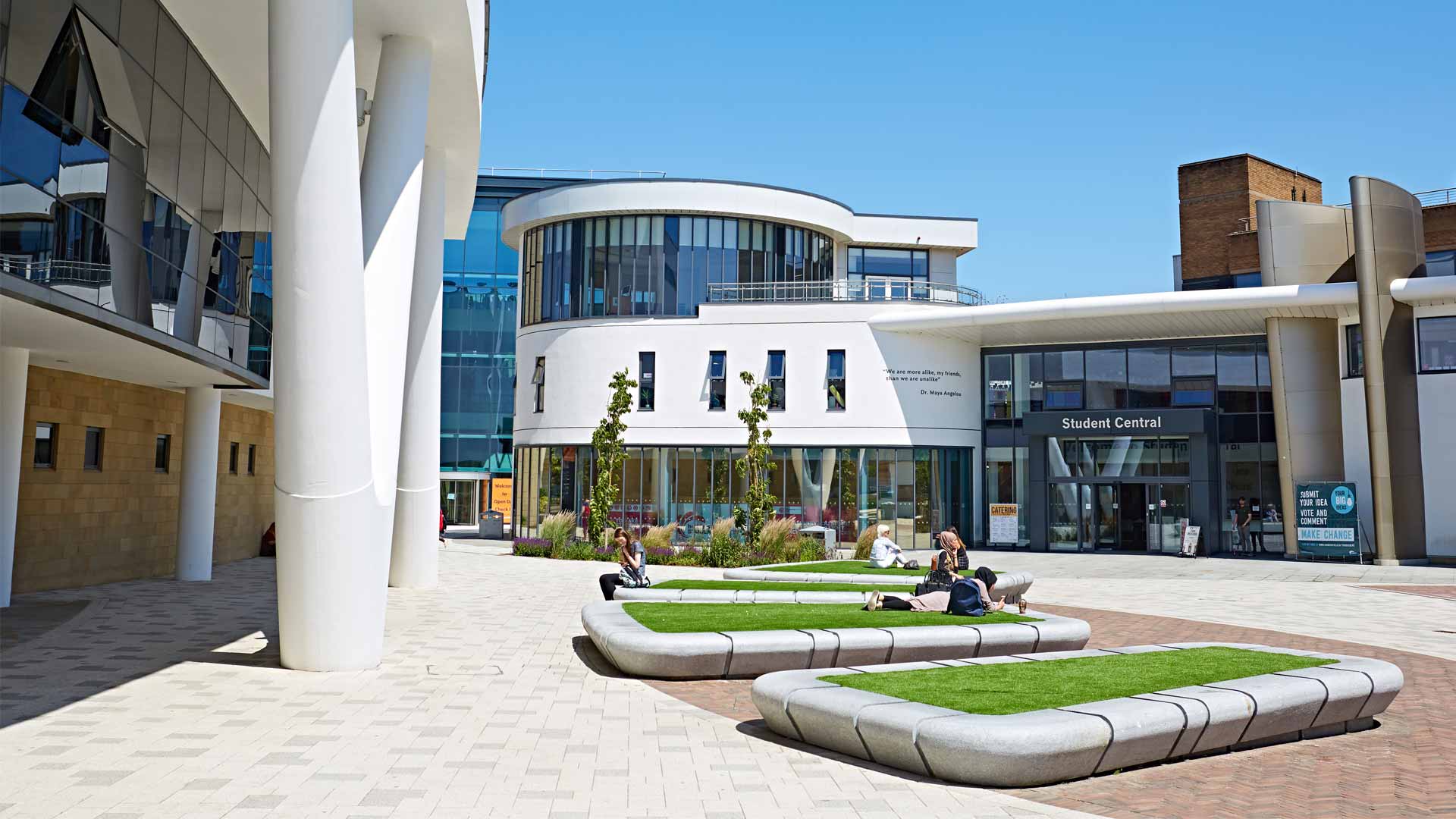 Students laying down in the University Plaza. The Student Central building is behind them.