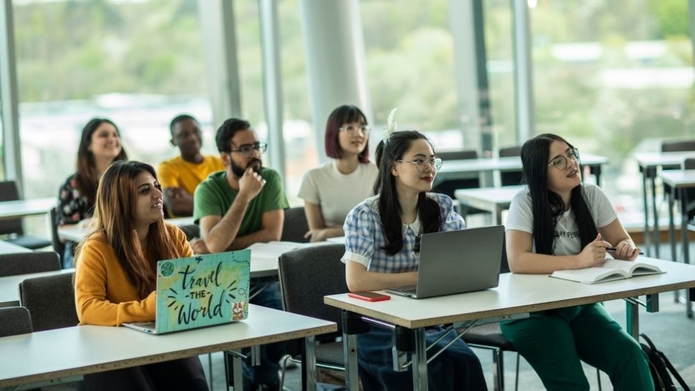 Students sat in a classroom looking up listening to the lecturer