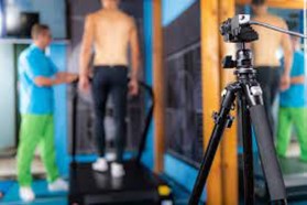 Photograph of a camera filming a person walking on a treadmill