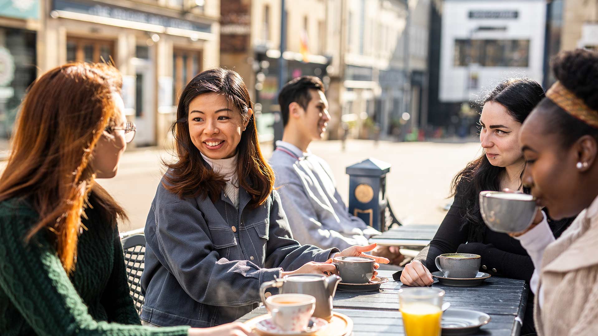 Student chating and drinking hot drinks outside of a cafe